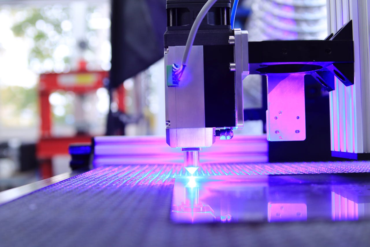 Close-up of a laser engraving machine working indoors with blue light reflection.